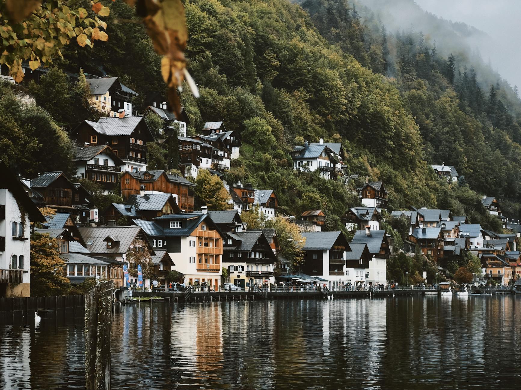 Górska wioska z drewnianymi domami nad spokojnym jeziorem we mgle